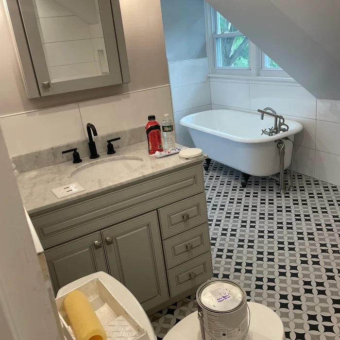 Bathroom vanity and freestanding bathtub in an attic room with patterned flooring.