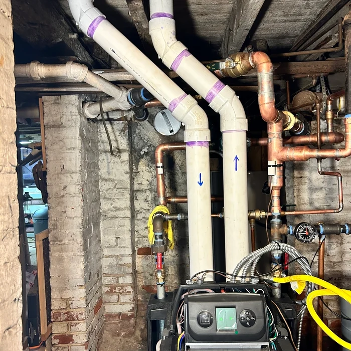 New copper connections and white pipe runs above the replacement boiler.