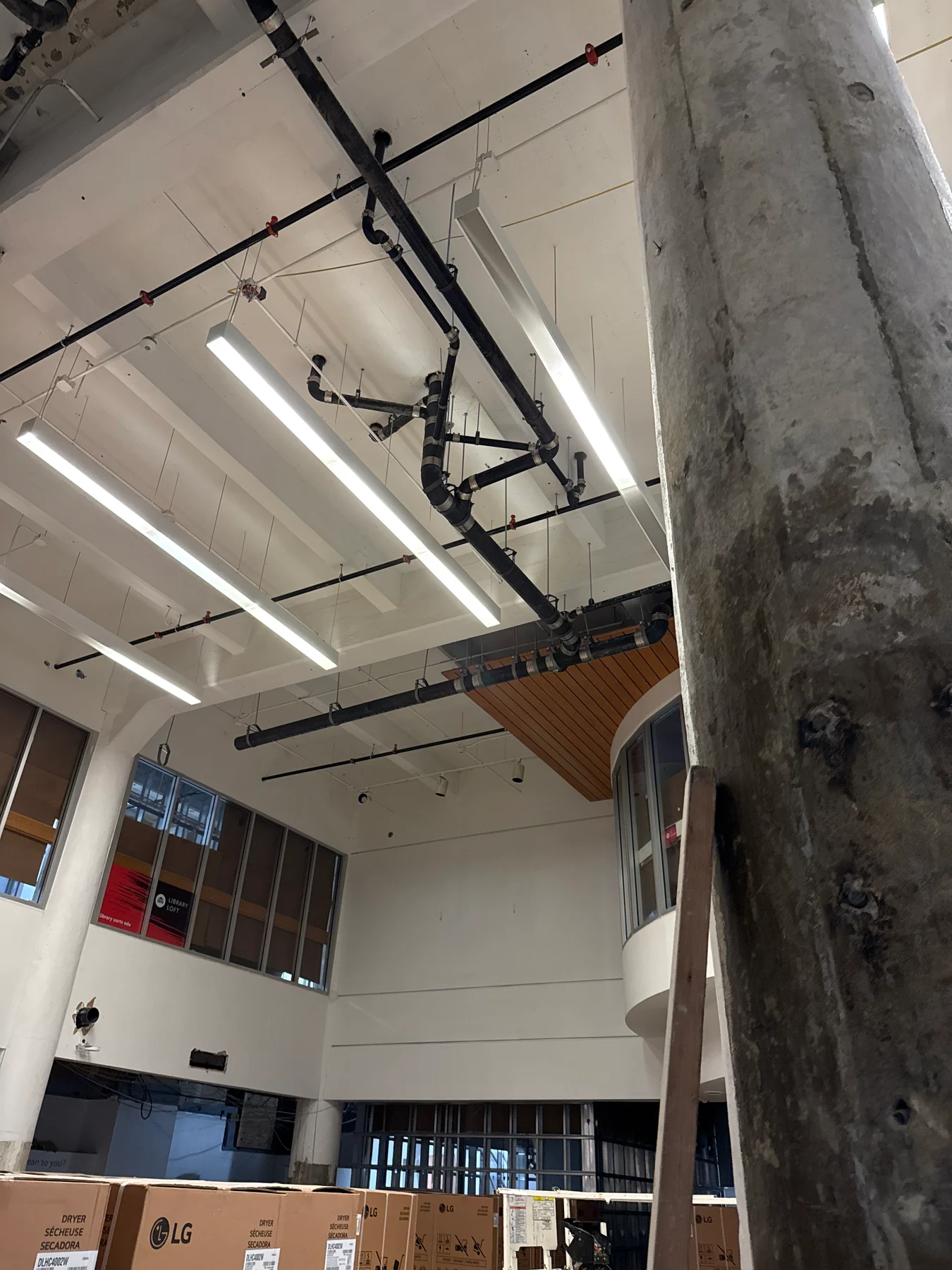 Large black drain pipes and branching connections suspended above a commercial interior.
