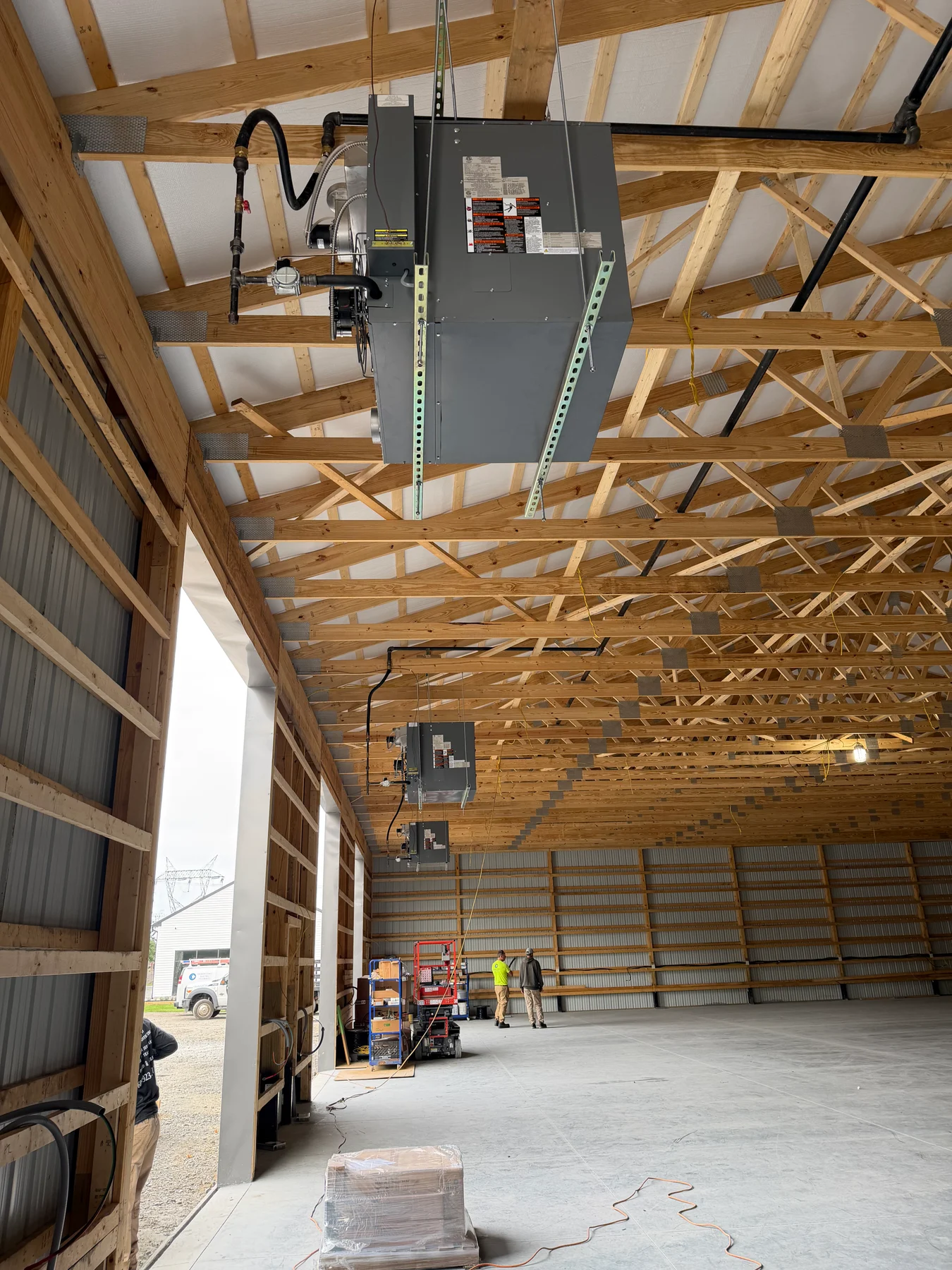 Gas piping and connections beside a suspended warehouse heater, with more heaters farther along the building.